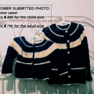 May include: Two crocheted cardigans, one adult and one child size, hang on a white hanger. The cardigans are navy blue with cream-colored stripes and white trim. The text "CUSTOMER SUBMITTED PHOTO" is visible.