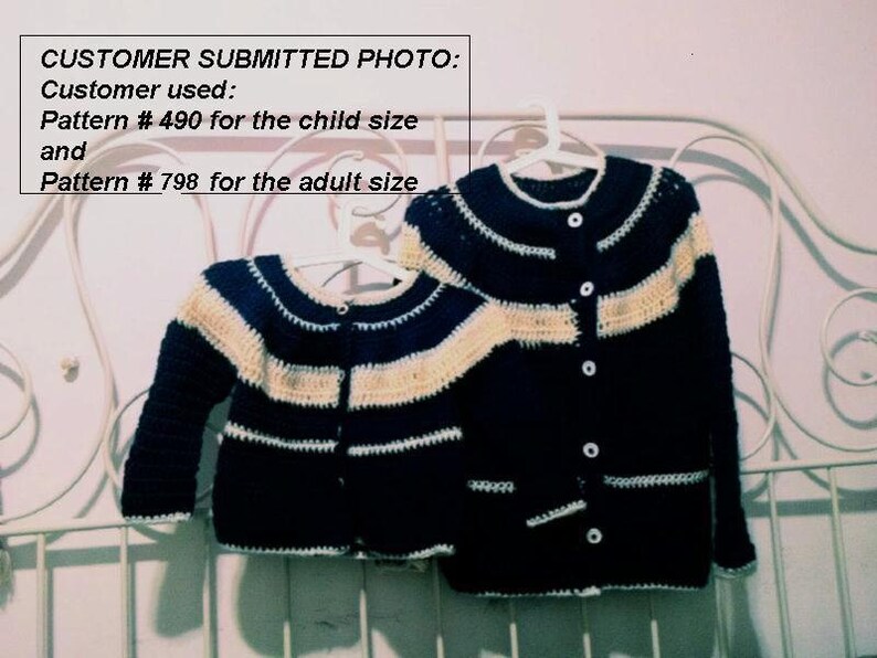 May include: Two crocheted cardigans, one adult and one child size, hang on a white hanger. The cardigans are navy blue with cream-colored stripes and white trim. The text "CUSTOMER SUBMITTED PHOTO" is visible.