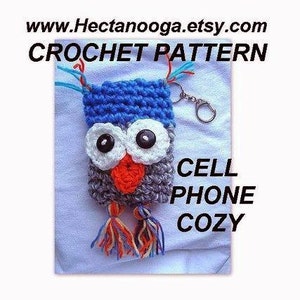 May include: Crochet pattern for a cell phone cozy shaped like an owl. The owl is gray, blue, white, and orange. It has big eyes and a beak. The cozy has a key chain attached.