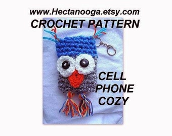May include: Crochet pattern for a cell phone cozy shaped like an owl. The owl is gray, blue, white, and orange. It has big eyes and a beak. The cozy has a key chain attached.