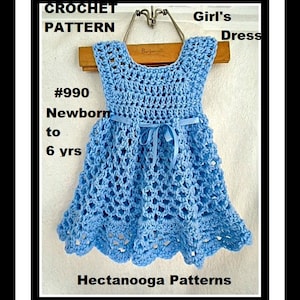Pu&ograve; includere: Schema a uncinetto per un vestito da bambina, #990, neonato a 6 anni. L'abito &egrave; azzurro chiaro con un motivo a uncinetto bianco e un nastro blu.