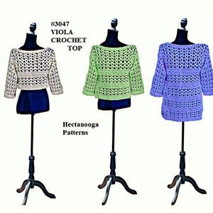 May include: Three crocheted tops in different colors: cream, light green, and lavender. The tops are displayed on mannequins and have a loose, open-weave design. The text "#3047 VIOLA CROCHET TOP" and "Hectanooga Patterns" are visible in the image.