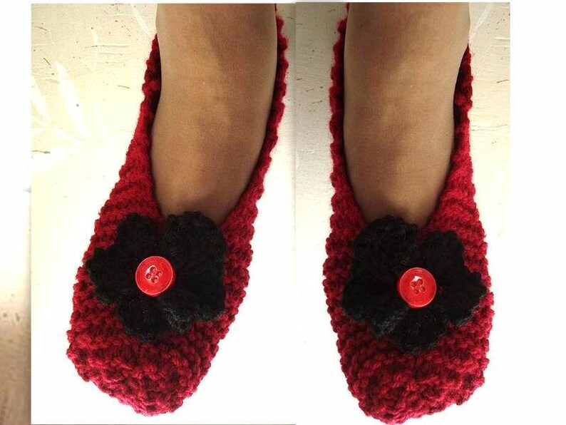 May include: A pair of red knitted slippers with black flower embellishments and red buttons.