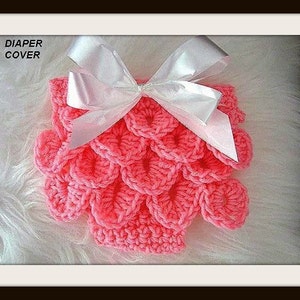 May include: Pink crocheted nappy cover with a white bow. "Diaper Cover" is written in white text on a black background.