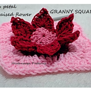 May include: A pink crochet granny square with a 6 petal raised flower in the center. The flower is red and pink. The text "6 petal raised flower" and "GRANNY SQUARE" is visible in the image.
