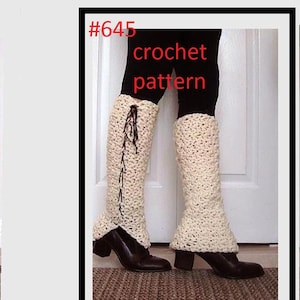 Puede incluir: Un par de polainas blancas de ganchillo con un detalle de encaje marrón. Las polainas se llevan sobre pantalones negros y las está modelando una persona. La imagen incluye el texto #645 crochet pattern.