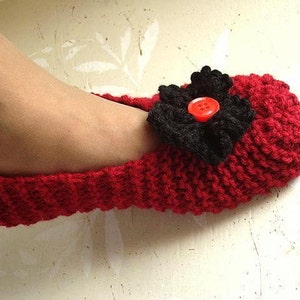 May include: Red knitted slipper with a black fabric flower and a red button in the center.