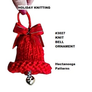 May include: Red knitted bell ornament with a silver heart charm. The bell has a red ribbon bow and the text "#3027 KNIT BELL ORNAMENT Hectanooga Patterns" is printed on a white background.