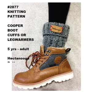 Könnte beinhalten: Graue gestrickte Stiefelmanschetten oder Beinstulpen mit einem braunen Lederlabel mit der Aufschrift "Hectanooga". Die Manschetten werden über braunen Lederstiefeln mit weißer Sohle getragen.