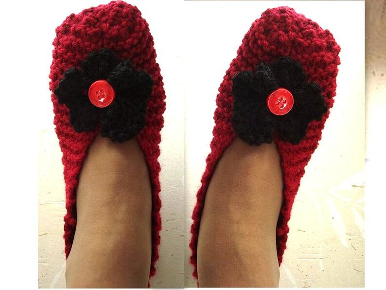 May include: Red knitted slippers with a black flower and a red button on the top.