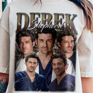 May include: White t-shirt featuring a collage of images of Derek Shepherd from the TV show Grey's Anatomy. The text "Derek Shepherd" is written in gold letters above the images.