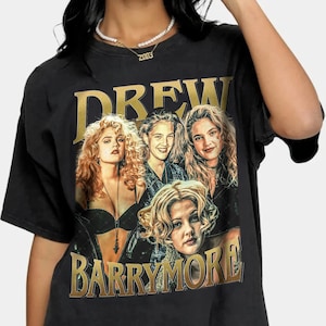May include: Black t-shirt featuring a gold graphic of Drew Barrymore and the text "DREW BARRYMORE". The graphic includes four images of Drew Barrymore. The shirt has short sleeves and a crew neck.