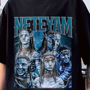 Puede incluir: Camiseta negra con un estampado gráfico de personajes de la película Avatar: El Camino del Agua. El texto "NETEYAM" está impreso en letras blancas grandes en la parte superior del gráfico.