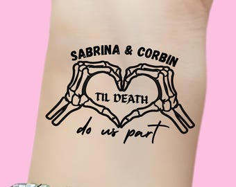 May include: A black temporary tattoo featuring a heart formed by skeleton hands. The tattoo includes the names "Sabrina & Corbin" above the heart and the phrase "Til Death do us part" within and below the heart.