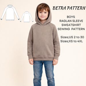 May include: A taupe hooded sweatshirt with raglan sleeves and ribbed cuffs, paired with blue jeans. The text reads BETRA PATTERN BOYS RAGLAN SLEEVE SWEATSHIRT SEWING PATTERN Sizes;US 2 to 30 Sizes;XS to 4XL, accompanied by two line art diagrams.