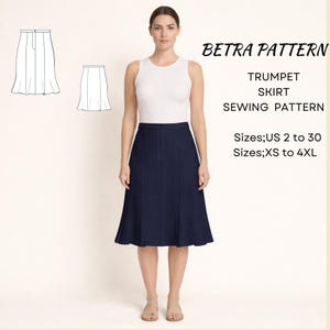 May include: A woman wearing a navy blue trumpet skirt and a white tank top. The image also shows a sewing pattern with the text "BETRA PATTERN TRUMPET SKIRT SEWING PATTERN" and size information.