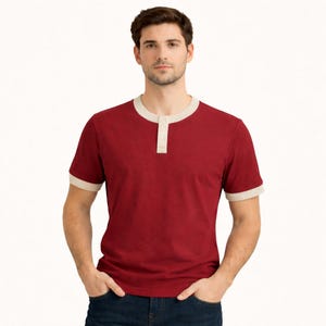 Könnte beinhalten: Burgunderfarbenes Henley-Shirt mit kurzen Ärmeln, cremefarbenem Kragen, Manschetten und Knopfleiste. Das Shirt ist aus weichem Stoff gefertigt. Das Model trägt eine dunkelblaue Jeans.