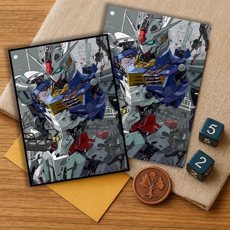 May include: Two art prints featuring a detailed illustration of a robot in shades of blue, white, red, and yellow. The prints are on a wooden surface with a beige cloth, two dice, a copper coin, and a yellow envelope.