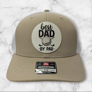 May include: A tan and white trucker hat with a white circle patch that says "best dad -by par- " with a golf ball and clubs in black. The hat has a black and red Richardson logo and says "Original 112 Trucker Adjustable"