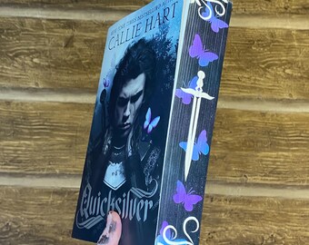May include: A paperback book titled "Quicksilver" by New York Times bestselling author Callie Hart. The cover features a dark-haired man with a sword and a butterfly design. The spine of the book has a decorative design with butterflies and a sword.