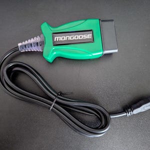 Może przedstawiać: Zielone narzędzie diagnostyczne do samochodów z czarnym złączem i czarnym kablem z złączem USB. Narzędzie ma nadrukowane słowo "MONGOOSE".