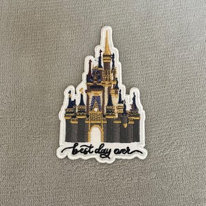 Puede incluir: Parche blanco bordado con una ilustración colorida del castillo de Cenicienta y el texto "best day ever".