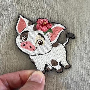 May include: Embroidered patch featuring a cartoon pig with white and brown spots. The pig has pink ears and snout, and a red flower crown. The patch is designed with black outlines and a smiling expression.