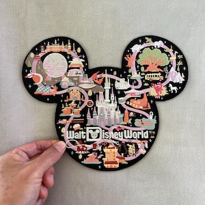 May include: A black, Mickey Mouse-shaped embroidered patch featuring a detailed map of Walt Disney World. The design includes colorful illustrations of park landmarks, attractions, and the text Walt Disney World in white lettering.