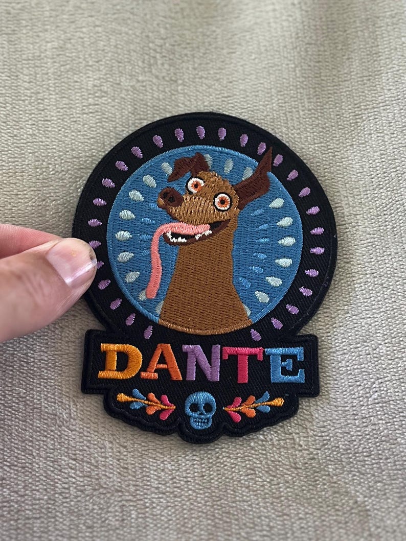 Dante patch from Coco with floral design & skull. 4x3 inch embroidered iron-on — perfect Disney Día de los Muertos accent for jackets & bags.