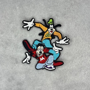 May include: Embroidered patch featuring two cartoon characters, one in an orange jacket and green hat, the other in a red shirt with a white "M". Both characters have white gloves and are set against a grey background.