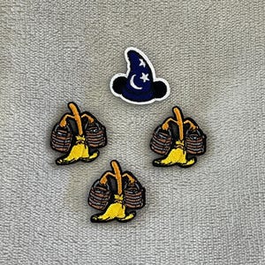 May include: Four embroidered patches on a gray background. Three patches depict a yellow banana with a brown basket on its back. A fourth patch shows a blue wizard hat with a crescent moon and stars.