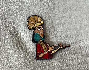 May include: Embroidered iron-on patch featuring a cartoon character with a gold crown and red and gold clothing. The character is pointing with both hands and has a smirk on their face.