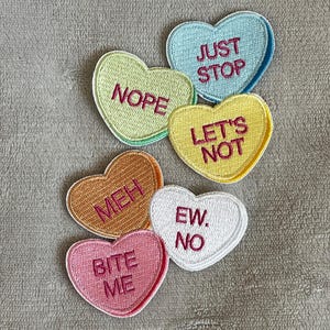May include: Six heart-shaped patches with different messages, including "Just Stop", "Nope", "Let's Not", "Meh", "Ew. No", and "Bite Me".
