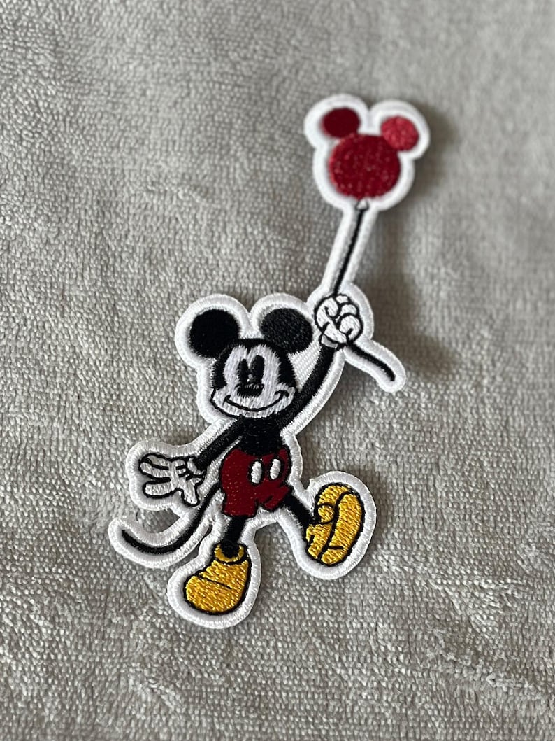 Add a touch of nostalgia with this vintage embroidered patch featuring Mickey Mouse holding a red balloon. Perfect for Disney fans and retro-inspired decor.