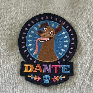 Dante patch from Coco with floral design & skull. 4x3 inch embroidered iron-on — perfect Disney Día de los Muertos accent for jackets & bags.