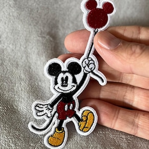 Add a touch of nostalgia with this vintage embroidered patch featuring Mickey Mouse holding a red balloon. Perfect for Disney fans and retro-inspired decor.