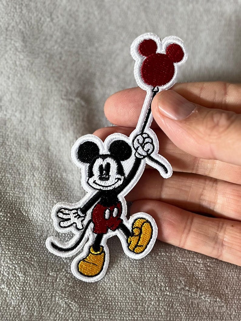 Add a touch of nostalgia with this vintage embroidered patch featuring Mickey Mouse holding a red balloon. Perfect for Disney fans and retro-inspired decor.