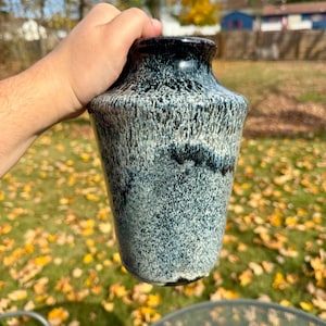 May include: A blue and white ceramic vase with a speckled glaze. The vase has a rounded bottom and a wide opening.