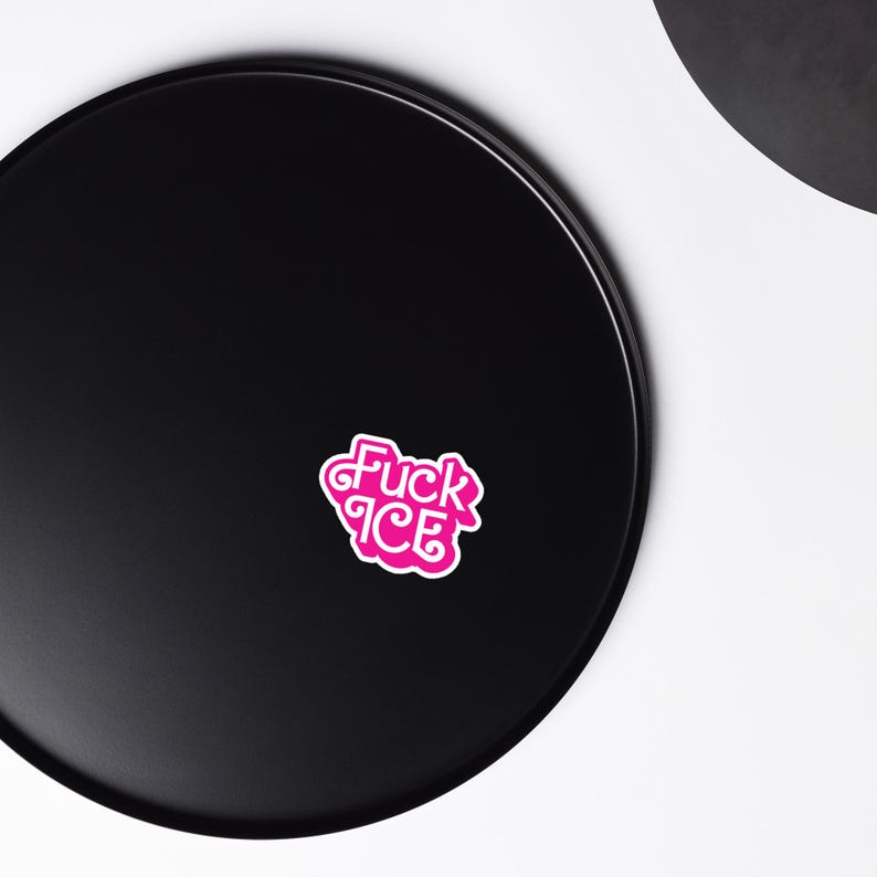 May include: A pink sticker with the words "Fuck ICE" in a stylized font. The sticker has a white border and is set against a black background.
