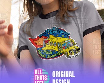 May include: A light gray ringer t-shirt with black trim featuring a graphic of a yellow school bus with wings and flames. The text reads Seatbelts Everyone! and PBS Needs Saving! with illustrations of cartoon characters inside the bus windows.
