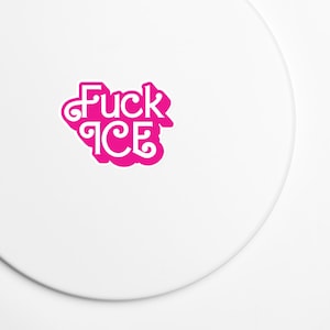 May include: A white sticker with the phrase "Fuck ICE" in a stylized, pink font. The text is arranged in two lines, with "Fuck" above "ICE". The sticker has a rounded, irregular shape.