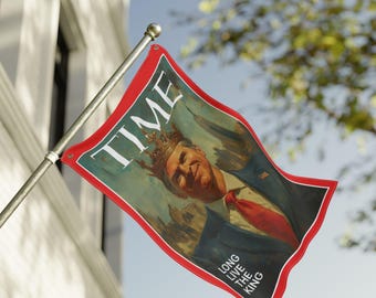 May include: A rectangular flag with a red border and the word "TIME" at the top. The flag features a portrait of a man wearing a crown, with the text "LONG LIVE THE KING" at the bottom. The flag is attached to a silver pole.