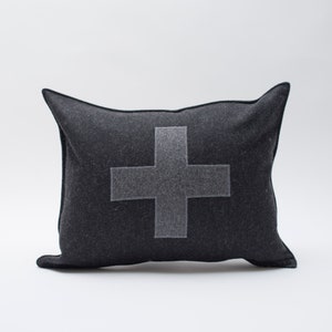 May include: A black rectangular cushion with a large grey embroidered Swiss cross in the centre.