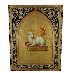 May include: A religious painting featuring a white lamb holding a flag with a red cross, resting on a book. The background is gold with sun rays emanating from behind the lamb. The frame is black with floral and geometric designs.