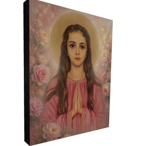 May include: A framed canvas art print featuring a portrait of a young woman with long brown hair, wearing a pink dress, and a gold halo. The background is filled with pink roses and soft lighting. The canvas has a black border.