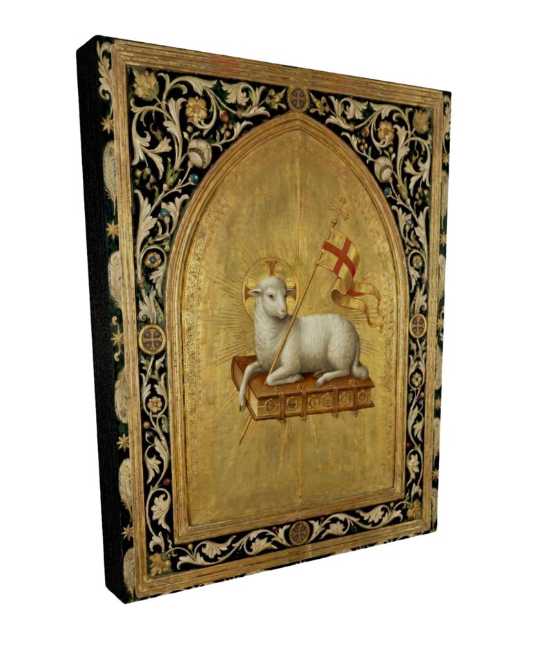 May include: A framed religious artwork featuring a lamb holding a flag with a cross. The lamb is resting on a book, set against a gold background. The frame has ornate floral and geometric designs in black and gold.