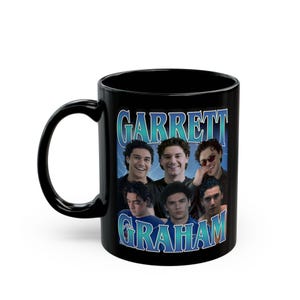 Puede incluir: Taza de cerámica negra con un collage de imágenes de una persona, con el texto "GARRETT GRAHAM" en un diseño azul y blanco. La taza tiene un asa curva.