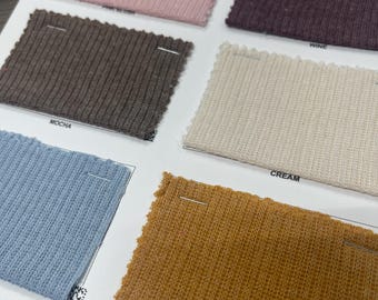 Pode incluir: Cartão de amostra de dez cores diferentes de tecido canelado. As cores são: rosa, marrom, creme, amarelo mostarda, azul claro, roxo escuro, verde escuro, cinza claro, cinza escuro e preto.