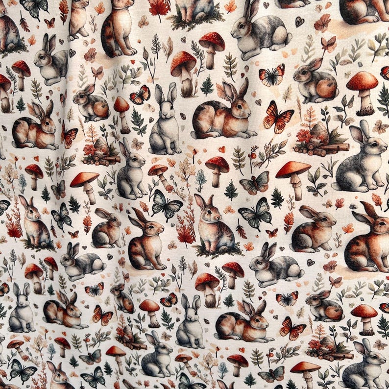 A close-up of fabric with a repeating pattern of rabbits, mushrooms, butterflies, and autumn leaves.