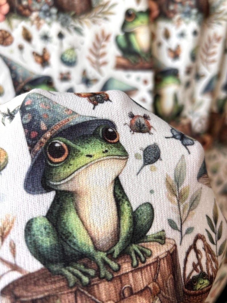 A close-up of a green frog in a wizard hat from the fabric pattern, with a blurred background of the same pattern.